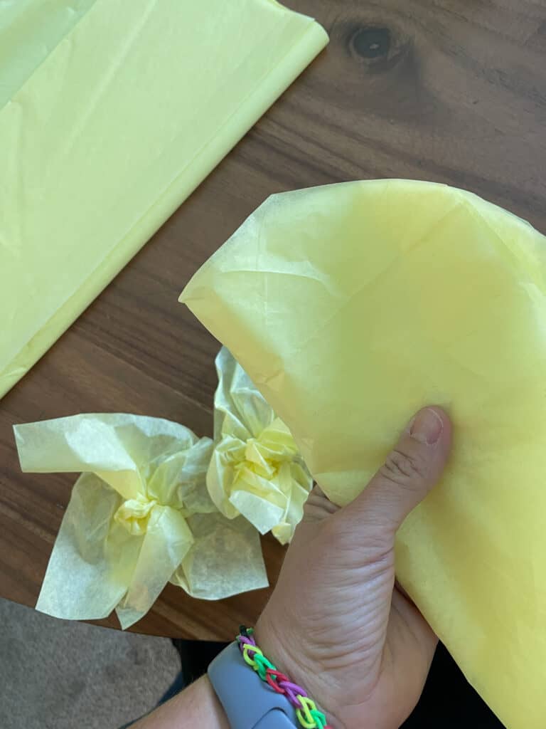 yellow tissue paper being folded and the edges rounded 