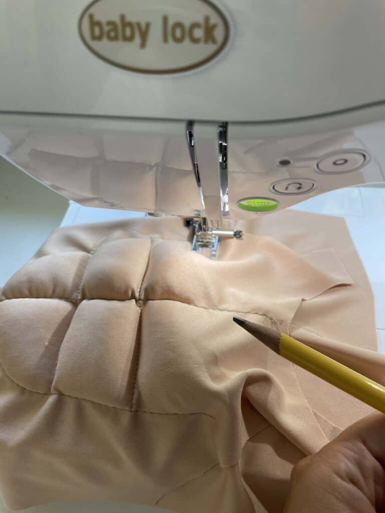 Nude fabric on a sewing machine with  stuffing being added for muscles