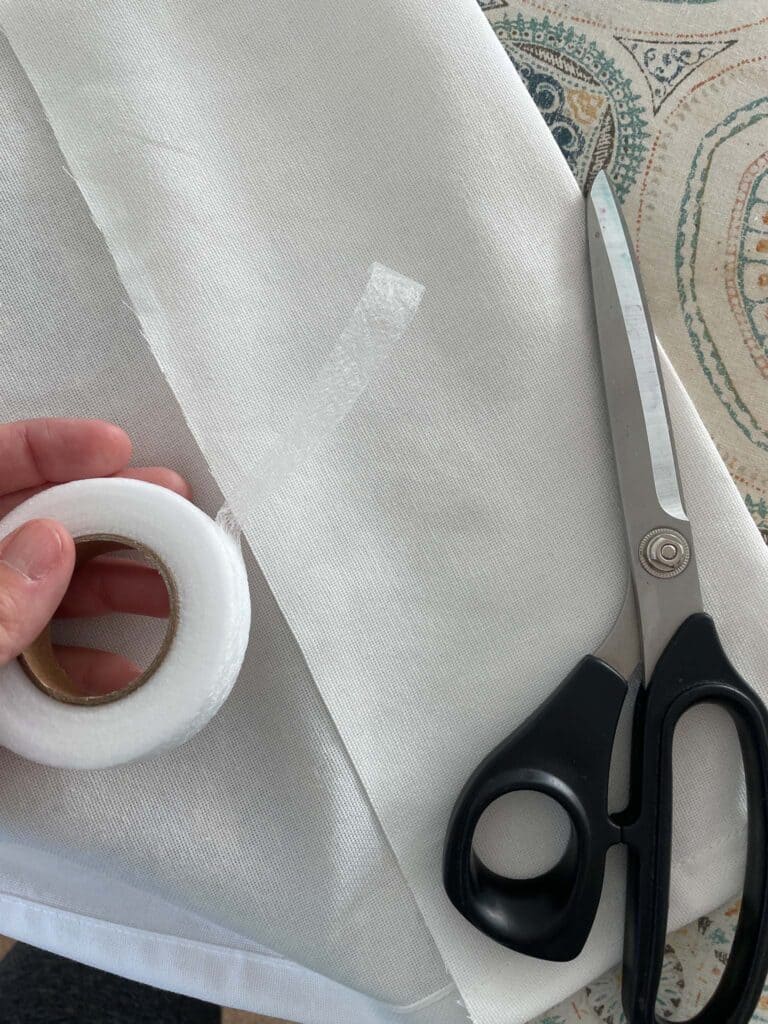 Hem tape and scissors laying on top of a curtain panel ready for hemming